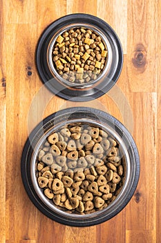 Dry kibble pet food. Dog or cat food in bowl on wooden table. Top view