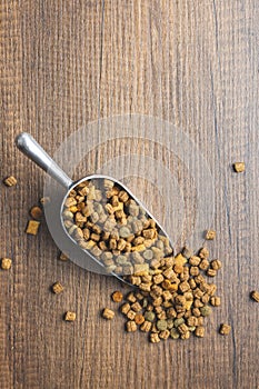 Dry kibble pet food. Dog or cat food in scoop on wooden table. Top view