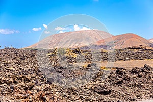 Dry lava field with volcans in background - Timanfaya national park