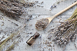 Dry lavender flowers bunches, essential lavender oil, lavender buds in big wooden spoon over wooden background. Flatlay