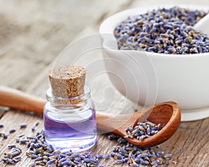 Dry lavender flowers in mortar and bottle of essential oil.