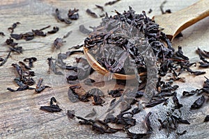 dry leaves of black tea in a wooden spoon.