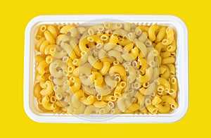 Dry macaroni on yellow background.