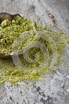 Dry Matcha tea in a small brown plate. Dark ceramic background