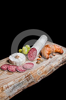 Dry meat sausage on a wooden plate with vegetables