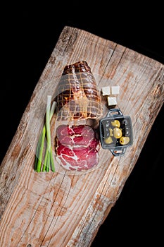 Dry meat and sausages with vegetables and cheese on a wooden table