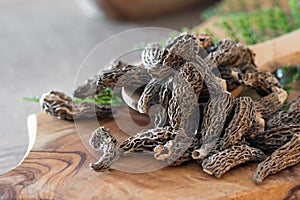 Dry Morel Mushrooms on Wooden Platter. Close-up of textured morel mushrooms, artfully arranged on a rustic wooden platter,