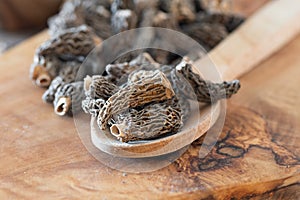 Dry Morel Mushrooms on Wooden Platter. Close-up of textured morel mushrooms, artfully arranged on a rustic wooden platter,