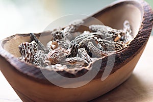 Dry Morel Mushrooms on Wooden Platter. Close-up of textured morel mushrooms, artfully arranged on a rustic wooden platter,