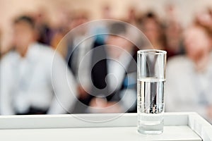 Dry mouth. Glass of pure water standing on tribune, podium provided for a public speaker to drink while giving a speech