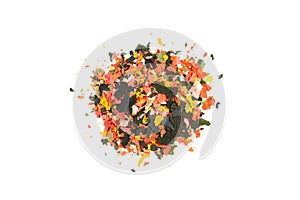 Dry multi-colored compound fish feed flakes in a transparent box on White background. Top view