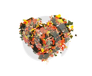 Dry multi-colored compound fishfeed flakes in the shape of a heart on White background. .