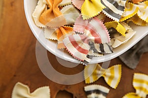 Dry multicolored Italian handmade macaroni called farfale, close-up in a white deep dish on a wooden background