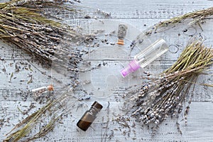 Dry natural lavender flowers, bottles with buds, essential lavender oil, organic perfume spray over wooden background