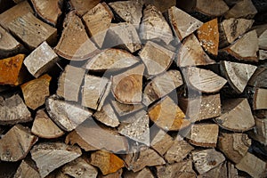 Dry oak firewood stacked in a pile, chopped wood for winter heating of the fireplace. Natural wood background