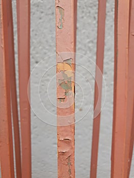 dry old paint peeling off metal bars from an old and uninstalled fence photo