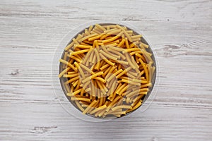 Dry Organic Maccheroni Pasta in a Bowl on a white wooden background, top view. Flat lay, overhead, from above