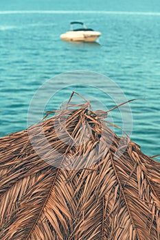 Dry palm leaf beach parasol for sun protection at seaside during summer holiday