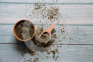 Dry parsley in a wooden bowl with a wooden measuring spoon on a wooden table. photo