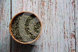 Dry parsley in a wooden bowl on a wooden table.