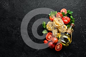 Dry pasta, tomatoes, greens, oil and ingredients. Italian traditional cuisine. Fresh vegetables. Top view.