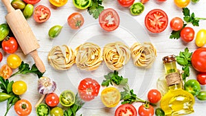 Dry pasta, tomatoes, greens, oil and ingredients. Italian traditional cuisine. Fresh vegetables. Top view.