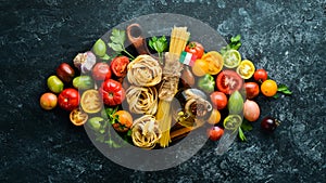 Dry pasta, tomatoes, greens, oil and ingredients. Italian traditional cuisine. Fresh vegetables. Top view.