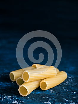 Dry pasta Tortiglioni closeup on a dark blue background.