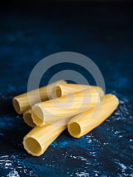 Dry pasta Tortiglioni closeup on a dark blue background.