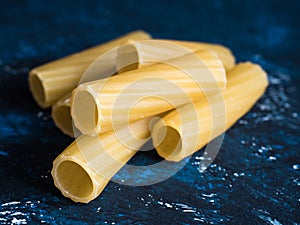 Dry pasta Tortiglioni closeup on a dark blue background.