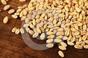Dry pearl barley with a handful on a wooden table.