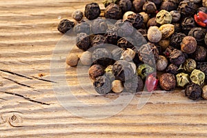 Dry peppercorn mix on wooden background