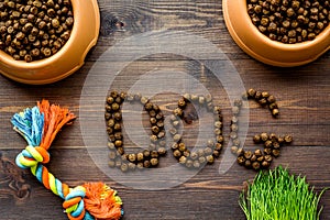 Dry pet - dog food in bowl with dog text on wooden background top view