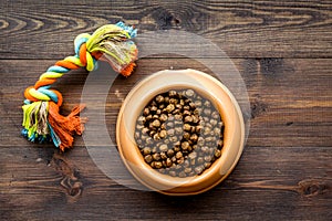 Dry pet - dog food in bowl on wooden background top view