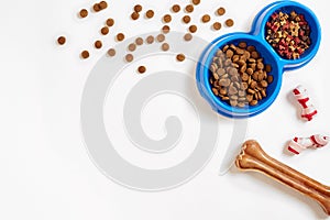 Dry pet food in bowl and bone on white background top view