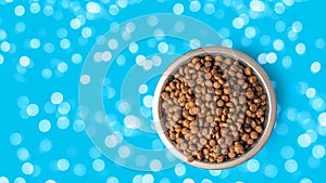 dry pet food in a metal bowl isolated on blue background, bokeh. Food for cats and dogs pattern.