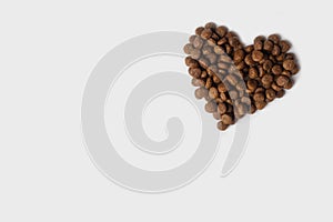 Dry pet food in the shape of a heart isolated on a white background. Granulated dietary food for cats and dogs