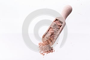 Dry pink clay mask for face and body in a wooden spoon. Isolated on a white