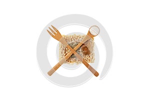 Dry pressed instant noodles with unhealthy spices are abstractly crossed out with a fork and spoon. Fast food with food additives