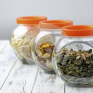 Dry pumpkin seeds in a glass jar on a white wooden board