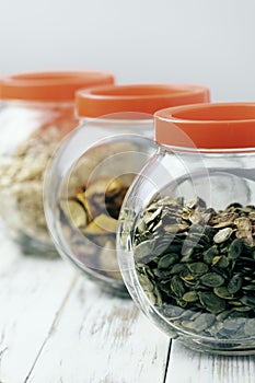 Dry pumpkin seeds in a glass jar on a white wooden board