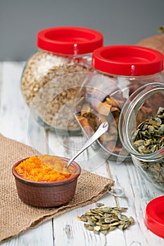 Dry pumpkin seeds in a glass jar on a white wooden board