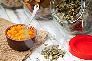 Dry pumpkin seeds in a glass jar on a white wooden board