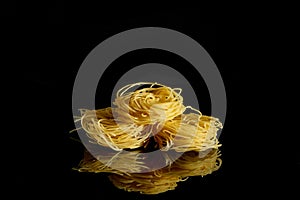Dry, raw egg pasta capelli , isolated on black background. Cooking concept. Top view with copy space photo