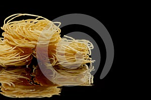 Dry, raw egg pasta capelli , isolated on black background. Cooking concept. Top view with copy space