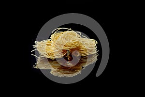 Dry, raw egg pasta capelli , isolated on black background. Cooking concept. Top view with copy space