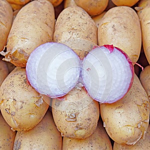 Dry red onion cut and open top view closeup on raw potatoes