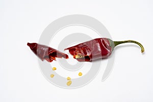 Dry red pepper pod with seeds on a white background. Broken dry pod in half