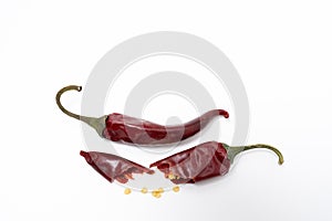 Dry red pepper pod with seeds on a white background. Broken dry pod in half