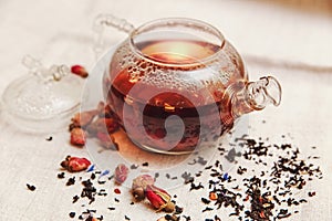 The Dry Red Small Roses with Black Tea in the Glass Teapot,Tea Drinking,Aromatized Flowers, Linen Tablecloth;Toned